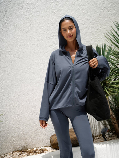 Modell med Balion Studio Flow Jacket Lunar Grey og hette oppe – bærer svart Balion tote bag utendørs